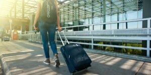 woman walking on pathway while strolling luggage